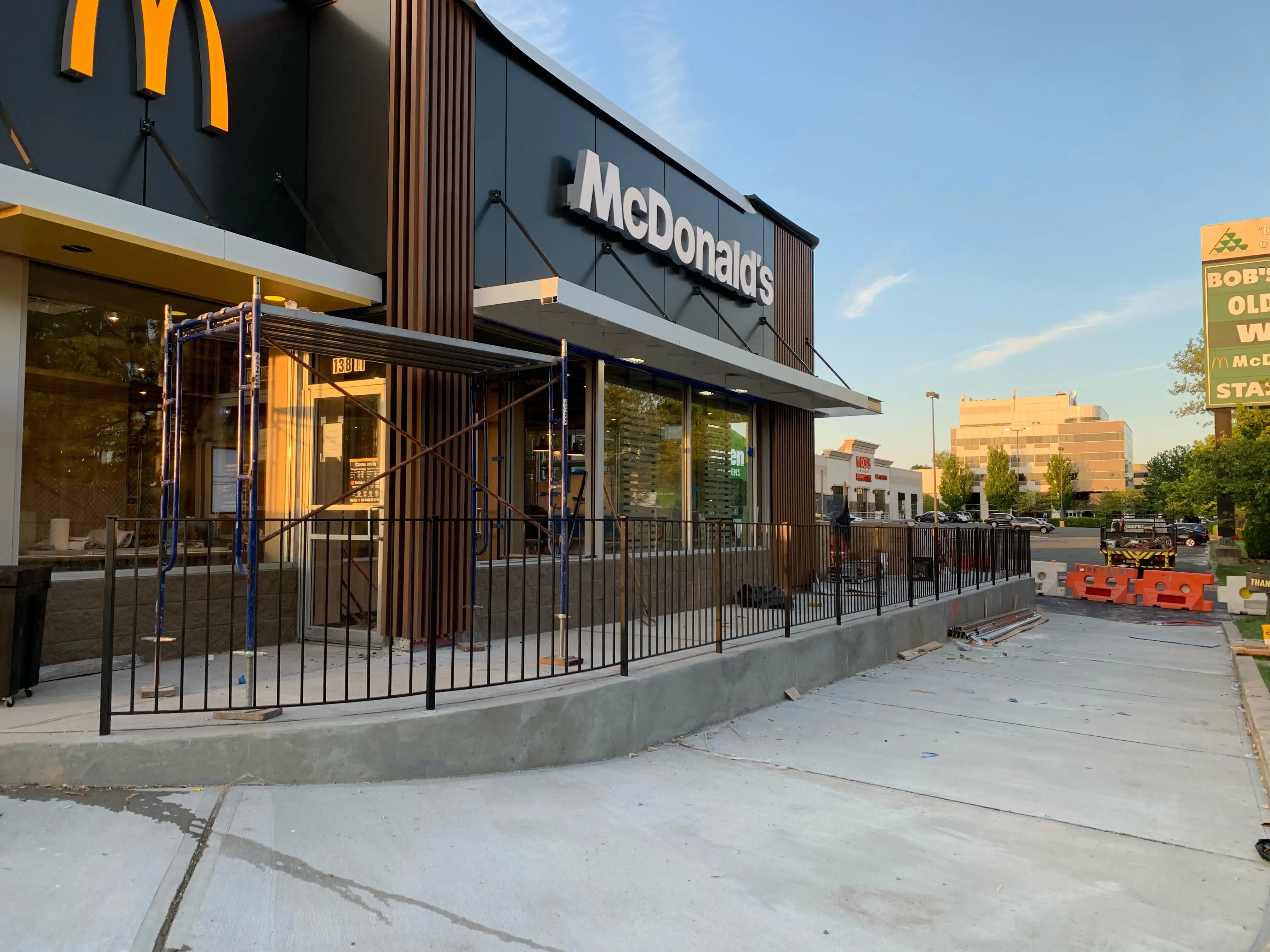 Black steel picket guardrail running along a commercial storefront forecourt