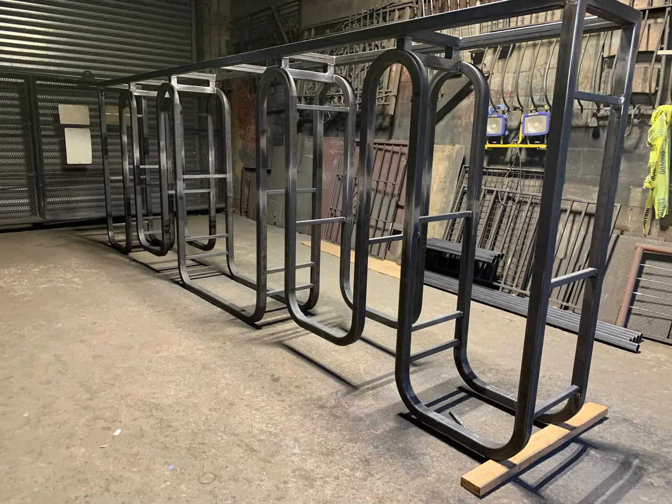 Row of welded steel window guard frames standing in line on the fabrication shop floor